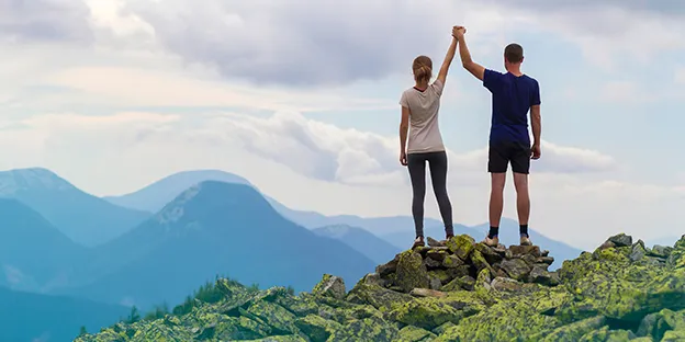 Mann und Frau auf einem Berggipfel – Symbolbild Erfolg