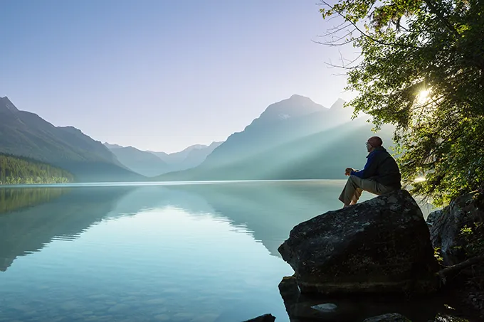 Mann sitzt allein an einem einsamen Bergsee