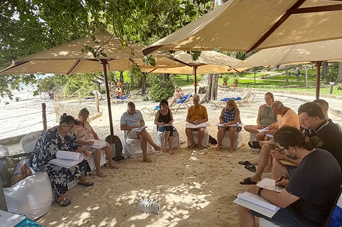 Seminarteilnehmer sitzen in einer Runde am Strand