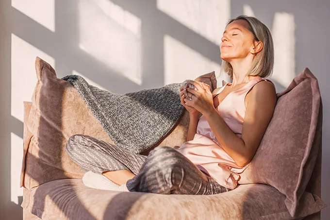 Ältere Frau mit Kaffeetasse auf dem Sofa